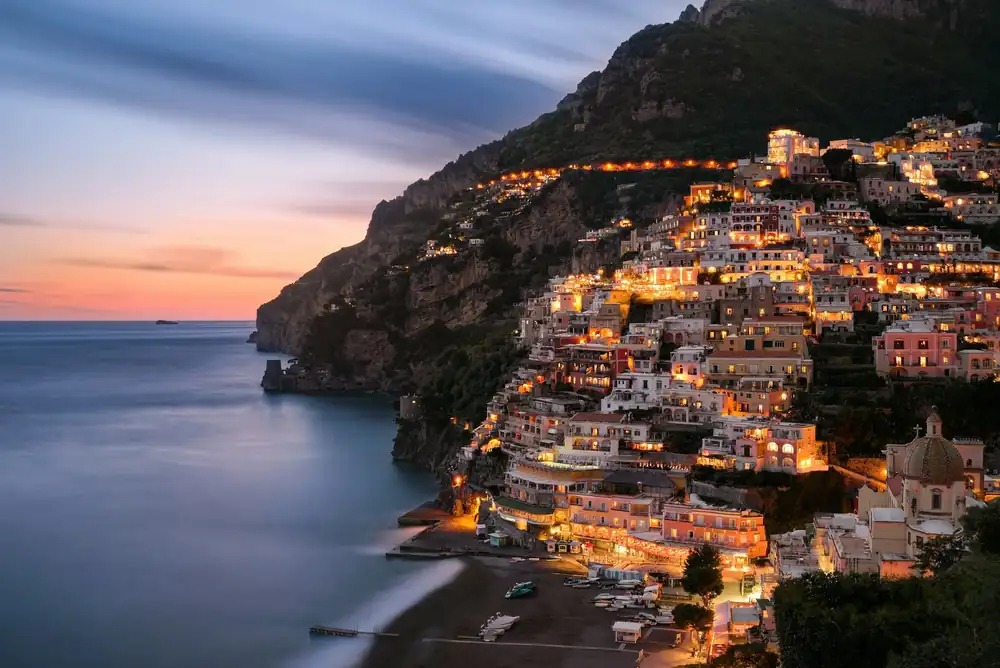 Positano on the Amalfi Coast at blue hour, lit-up houses above the sea